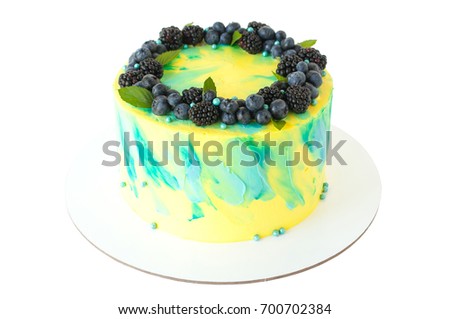 Cake with whipped yellow and green cream, fresh blueberries, blackberry and leaves, decorated with blue confectionery sprinkles. Picture for a menu or a confectionery catalog. Isolated.