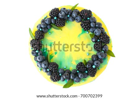 Cake with whipped yellow and green cream, fresh blueberries, blackberry and leaves, decorated with blue confectionery sprinkles. Picture for a menu or a confectionery catalog. Top view. Isolated.