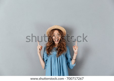 Picture of smiling young caucasian lady pointing at copyspace. Looking camera.