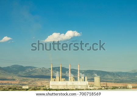Coal power plant with smoke from the chimneys next to a road shot from a car during driving