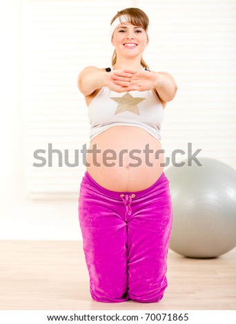 Smiling beautiful pregnant woman doing fitness exercises at home