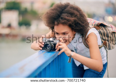 Mixed race tourist using camera while standing on the bridge