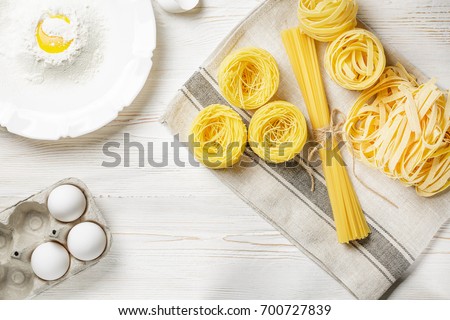 Raw pasta with ingredients on the white wooden table. Top view. Different kinds of pasta. Various types of pasta. Italian cuisine. Free space for text. Pasta background. Flour and eggs.