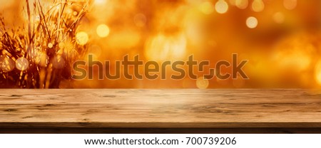 Radiant orange golden autumn background with an empty rustic wooden table for a concept decoration