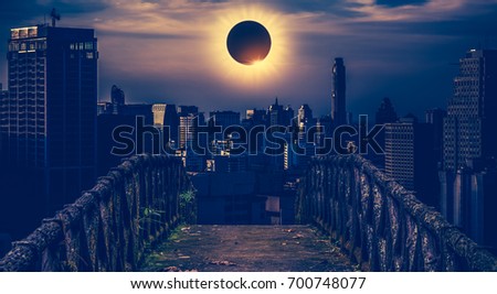 Amazing scientific natural phenomenon. The Moon covering the Sun. Total solar eclipse with diamond ring effect glowing on sky above skyscrapers with old concrete bridge. Serenity nature background.