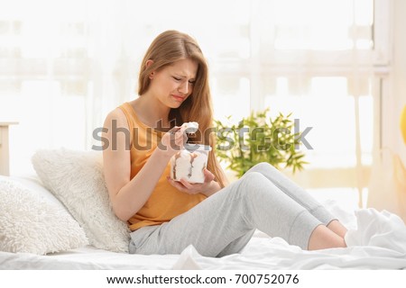 Emotional pregnant woman eating ice-cream in light room. Pregnancy hormones concept Royalty-Free Stock Photo #700752076