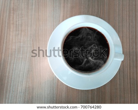 warm black coffee cup with white smoke in side put on the wooden table show the coffee still heat, top view of coffee can write your text in area left side of picture