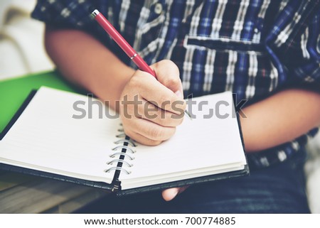A young boy writing on notebook diary. Back to school homework day. Royalty-Free Stock Photo #700774885