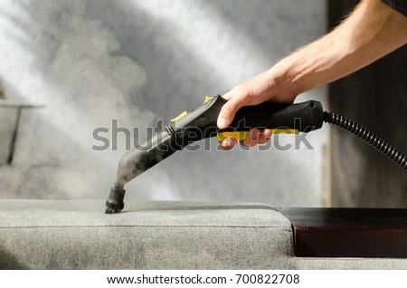 Hand cleaning sofa with a steam cleaner. Home cleaning concept. Royalty-Free Stock Photo #700822708