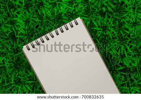  blank spiral notebook paper on green artificial grass mat
