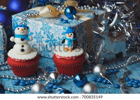 Christmas cupcakes with colored decorative snowman and penguin made from confectionery mastic, soft focus background