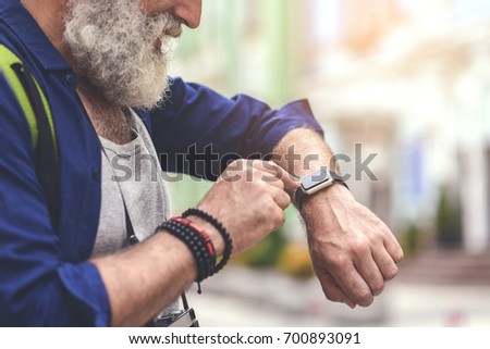 Cheerful old man touching screen of his watch
