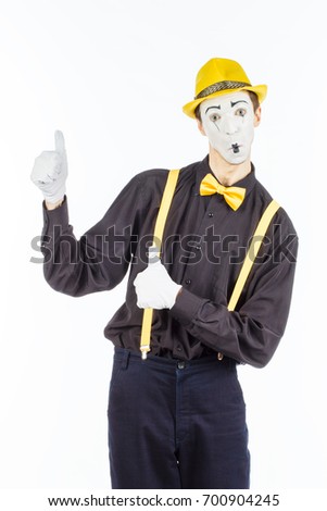 Portrait of a male, pantomime actor looking at camera and showing thumb up, standing on white background