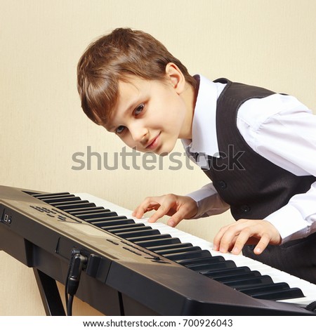 Young beginner pianist in a suit playing the electronic piano 