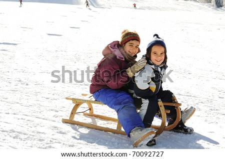 Happy children sledding on snow, mountain park
