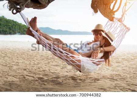 Asian couple lying on hammock on beach thailand Royalty-Free Stock Photo #700944382