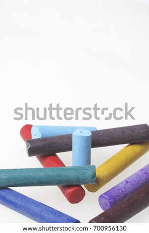 Crayons pastels in different colors. Lying in a box in their places. On a white background. In a chaotic order.