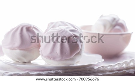Still life in pastel colors with pink and white marshmallows on a white plate with a napkin
