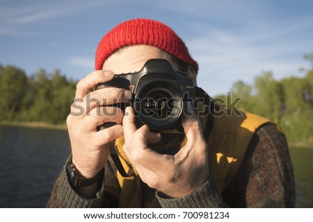 Closeup Portrait of a Man Taking a Picture with Professional Photo Camera on a Lake.