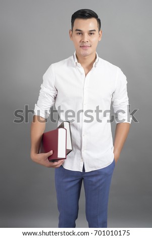 Portrait of man University student holding book in studio grey background