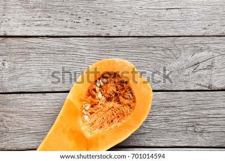 Ripe big pumpkin cut on wooden background. Autumn vegetables harvest and cooking concept, top view with copy space