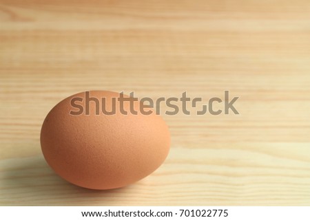 One fresh uncooked hen egg isolated on the wooden table, with free space for text and design 