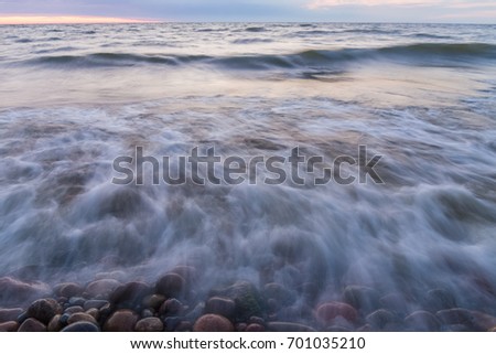 Small waves rolls ashore the rocky beach in the evening.