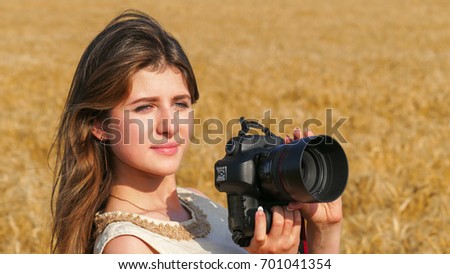 Tourist travel photographer with big black camera on the field summer day, close up portrait.