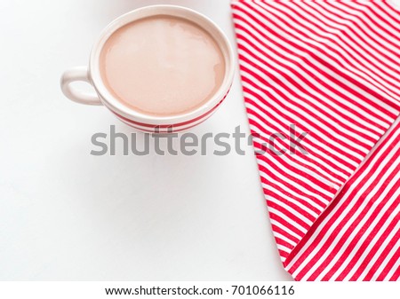 Red coffee cup over kitchen red strips towel. View from above. Isolated on white background