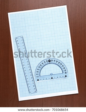 Drawing tools and blue plot paper on brown wood background