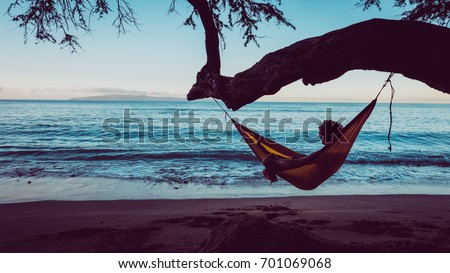Traveler guy is relaxing in a hammock hang on tree directly on the beach. Man take a chilling moment during adventure vacation and enjoy the beauty of the Nature. Wanderlust and travel concept. Royalty-Free Stock Photo #701069068
