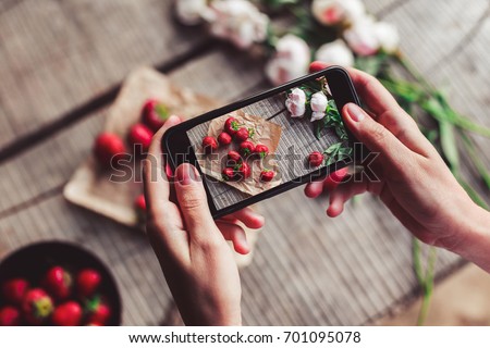 Girl's hands taking photo of breakfast with strawberries by smartphone. Healthy breakfast, Clean eating, vegan food concept. Top view