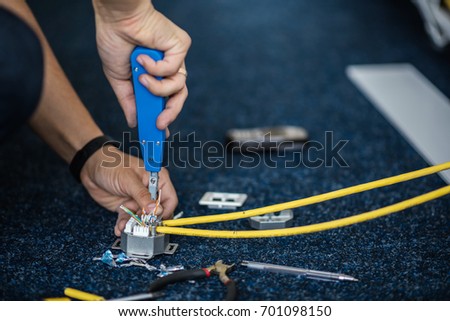 Worker connect a network cable with RJ45 sockets by punch-down tool, process of laying the local network