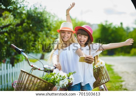 Two stylish teenage girlfriends on bicycle. Best friends enjoying day on bike