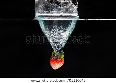 A strawberry splashing into water