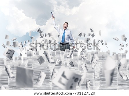 Businessman keeping hand with book up while standing among flying papers with cloudly skyscape on background. Mixed media.