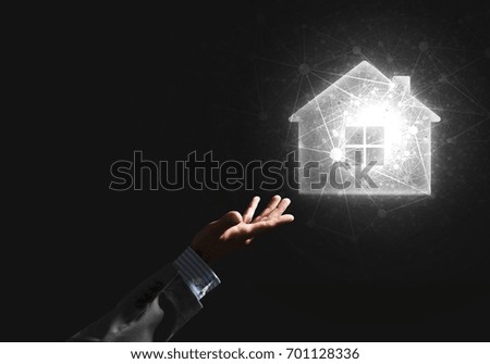 Businessman hand presenting glowing home icon or symbol