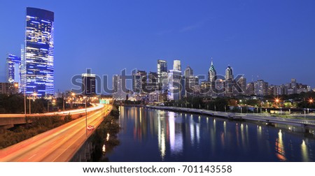 The skyline of Philadelphia of dusk. Schuylkill expressway traffic runs parallel to Schuylkill River.