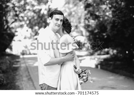 Black and white photo of wedding couple in love hugging in summer park. Groom looking at camera and smiling. Love, relationships, wedding and celebration concept.