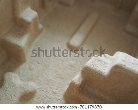 Brown sand like texture foam box, with 3D abstract shapes embossed like a alien building in the desert
