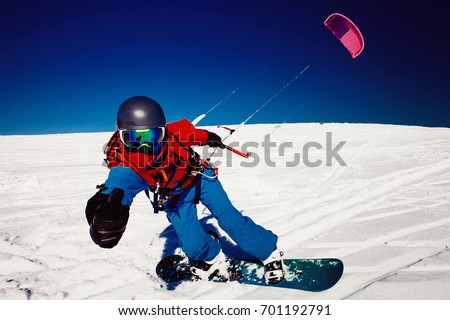 Snowboarder with kite on fresh snow in winter in tundra clear blue sky. Concept of sports snowkite. Royalty-Free Stock Photo #701192791