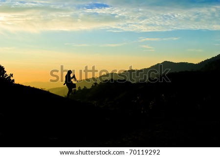 Silhouette of photographer on the mountain over the twilight sky