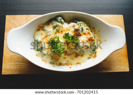 Spinach lasagna or Baked Spinach with Cheese in white bowl on black wooden table, tone picture