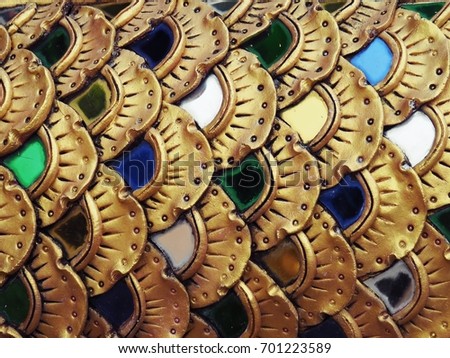 Closeup shot of gold dragon / fish scales stucco art decorated with colorful stained glasses / mirrors for backdrop, background, or wallpaper.