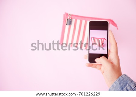 young women taking photo to bags with cell telephone or smartphone digital camera for Post to sell Online on the Internet . Customise pastel bright colors tone .
