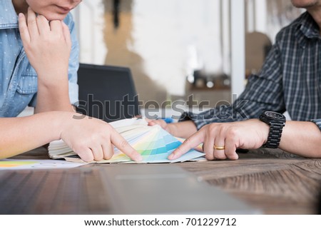asian graphic or interior designer choosing a colour from color swatch sampler or catalogue palette guide