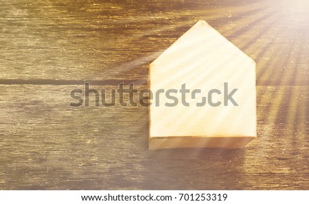 Miniature of small paper house with dollar symbol isolated on wooden background. Mortgage, real estate property, building saving and financing concept.