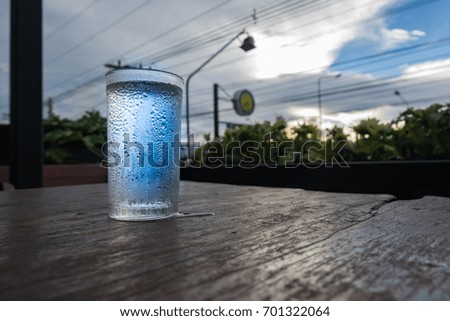 water and droplet in glass on wooden table on dark evening on blue sky background
