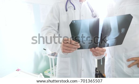 Medical workers in hospital examine x-ray prints. Male medics consult with each other while looking at x ray image. Two caucasian doctors view mri picture and discussing about it. Close up.