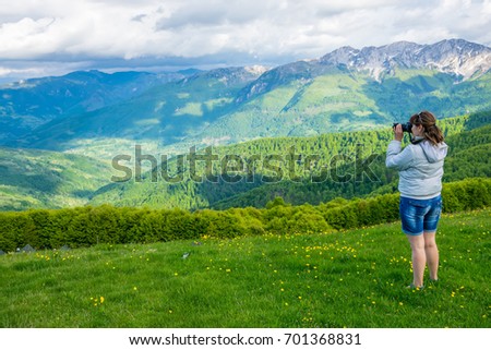The girl photographer shoots the top of the mountain Komovi. Montenegro.